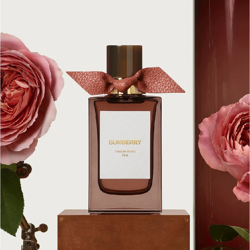 Perfume bottle with pink ribbon and pink roses in the background