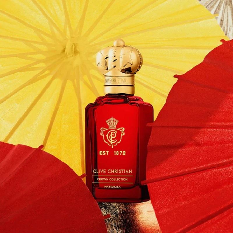 Red Clive Christian perfume bottle with gold cap against a yellow and red background