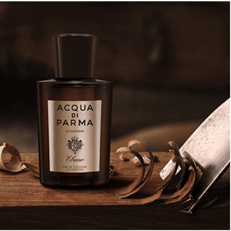 Lifestyle image of bottle Acqua di Parma cologne bottle on a wooden surface with dried leaves and a book.