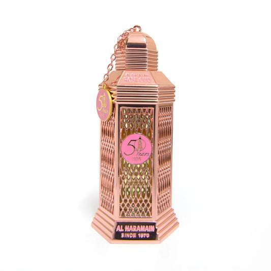 A pink colored bottle of Rose Oud Eau de Parfum by Al Haramain with a decorative cap and label, displayed against a white background.