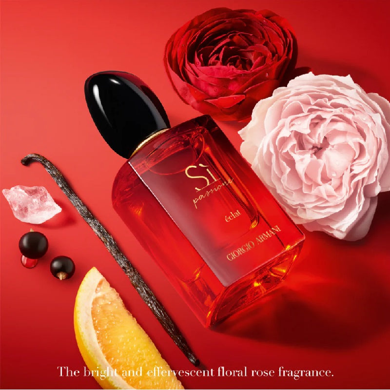 Perfume bottle with red and pink roses, vanilla bean, and orange slice on a red background