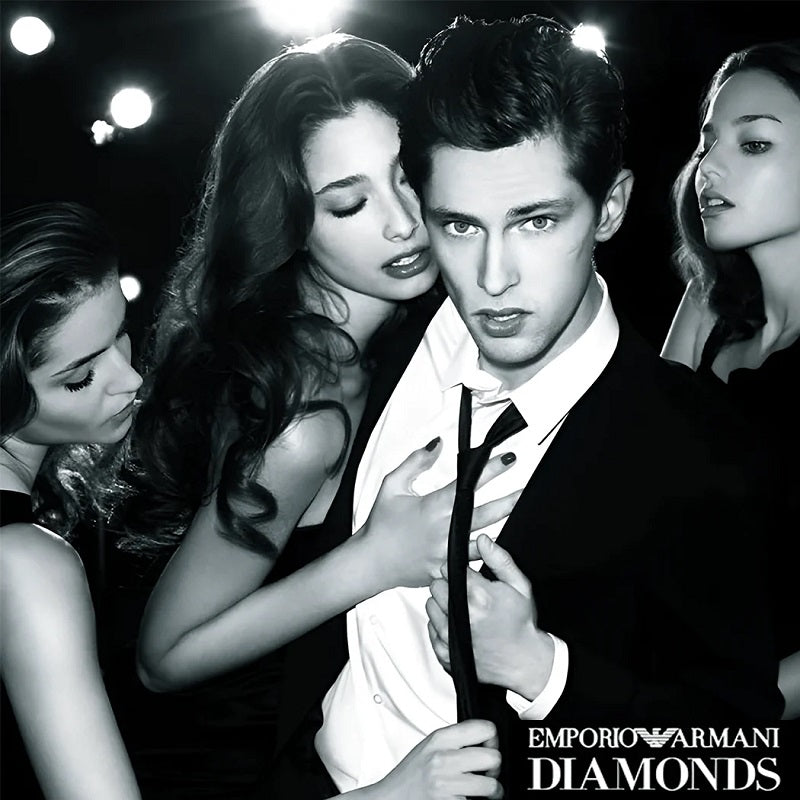 Black and white advertisement featuring a man in a suit with women around him, Emporio Armani Diamonds branding.