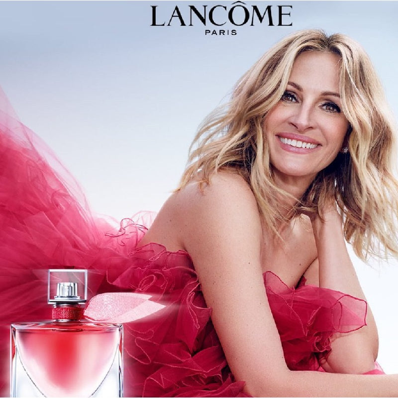 Woman in a red dress with a Lancème perfume bottle on a light blue background