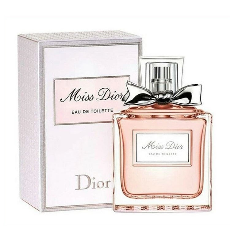 A product image featuring the Miss Dior (100ml) Eau de Toilette by Dior, with the bottle displayed in front of its packaging box. The bottle is clear with a pink liquid visible inside and is sealed with a silver cap.