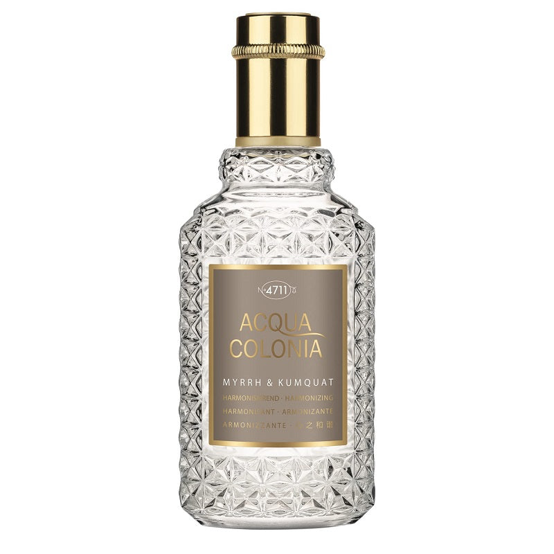 A clear glass bottle with a gold-colored label and a golden cap, labeled 4711 Acqua Colonia Myrrh + Kumquat.