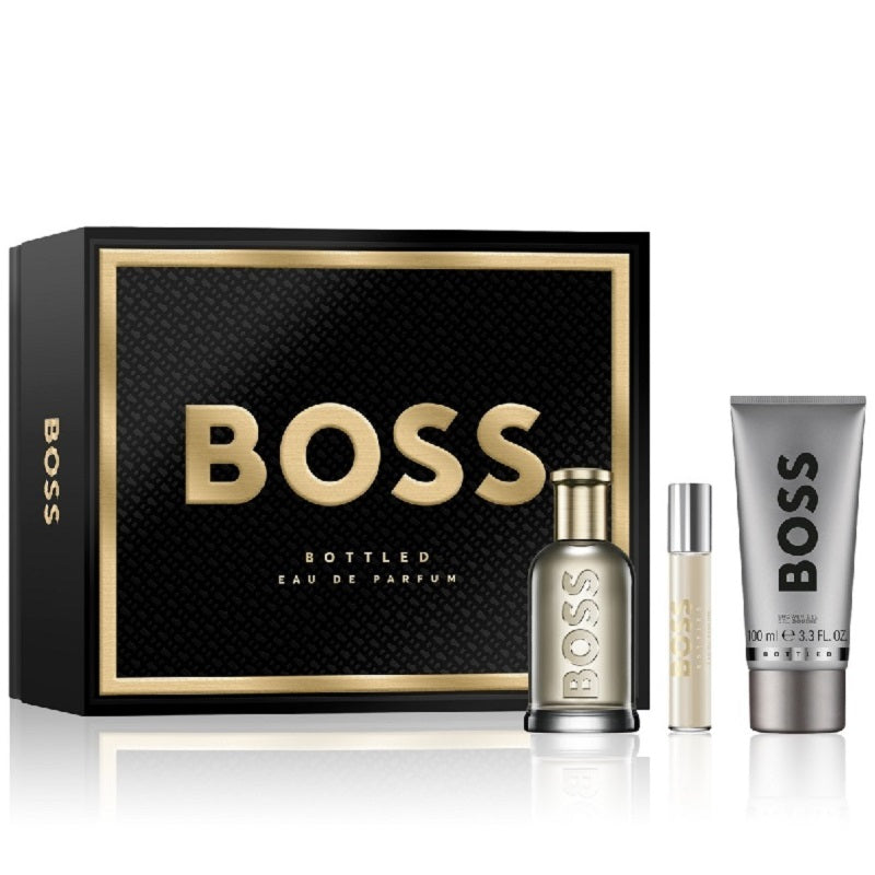 Boss Bottled Gift Set by Hugo Boss, containing a 100ml Eau De Parfum Spray bottle, a travel spray, and a 100ml Shower Gel tube, all presented in a black box with gold accents.
