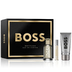 Boss Bottled Gift Set by Hugo Boss, containing a 100ml Eau De Parfum Spray bottle, a travel spray, and a 100ml Shower Gel tube, all presented in a black box with gold accents.
