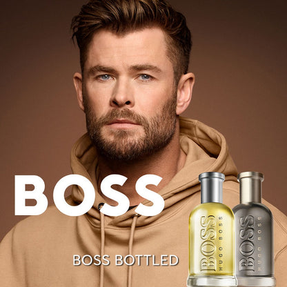 Man wearing a beige hoodie with Boss Bottled perfume bottles displayed.