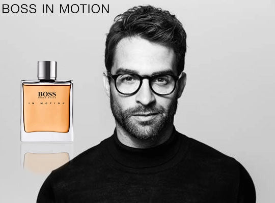 Man wearing glasses with a Hugo Boss perfume bottle on a gray background