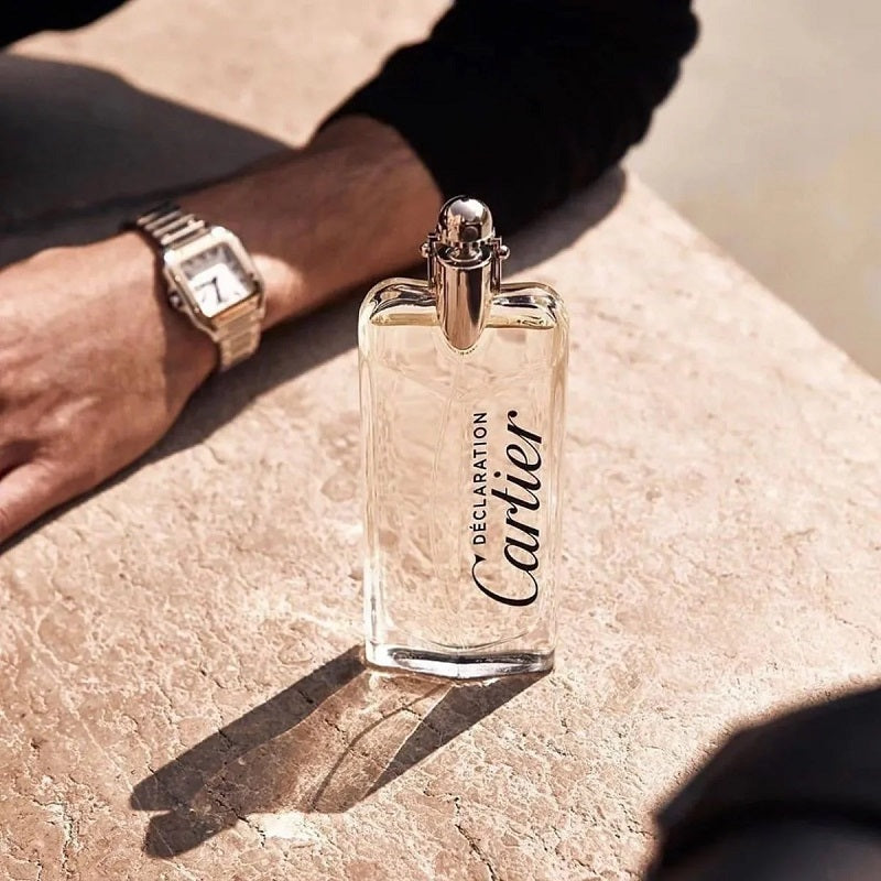 Cartier perfume bottle on a stone surface with a hand wearing a watch in the background