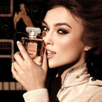 Woman holding a Chanel Coco perfume bottle with a blurred background