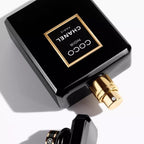 Black Chanel perfume bottle with gold cap on a white background
