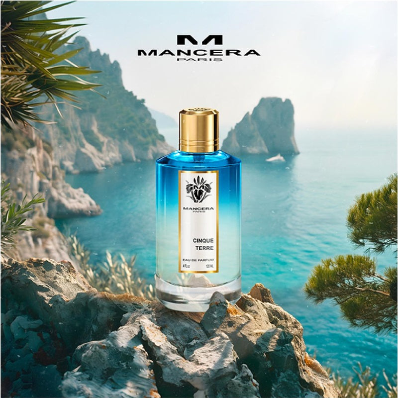 Perfume bottle on a rocky cliff with ocean and mountains in the background