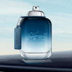 Blue perfume bottle with a car keychain on a reflective surface.