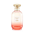 A bottle of Coach Dreams Sunset Eau de Parfum with a pink gradient and a gold-colored cap.