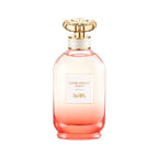 A bottle of Coach Dreams Sunset Eau de Parfum with a pink gradient and a gold-colored cap.