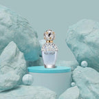 Perfume bottle labeled 'Daisy Dream' by Marc Jacobs on a blue platform with a light blue background