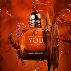 Perfume bottle with floral elements on an orange background, featuring the text 'Stronger with You Absolutely' and 'Emporio Armani'.