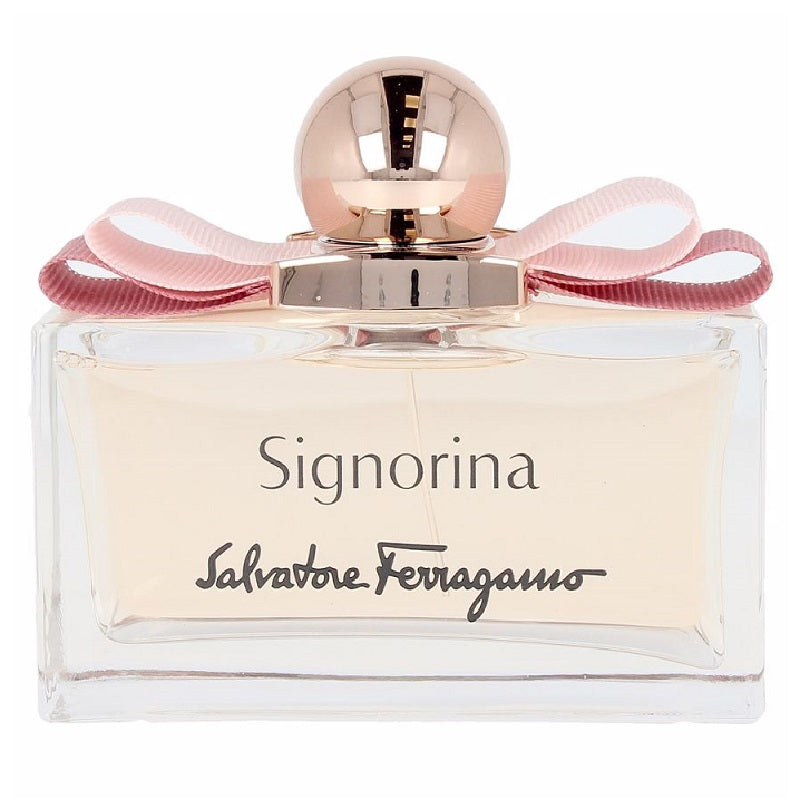 A bottle of Signorina Eau de Parfum by Salvatore Ferragamo with a clear design, pink ribbon, and gold cap.