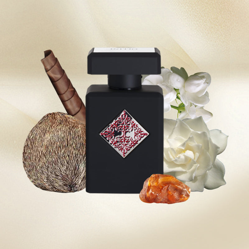 Black perfume bottle with decorative label, coconut, amber stone, and white flowers on a beige background