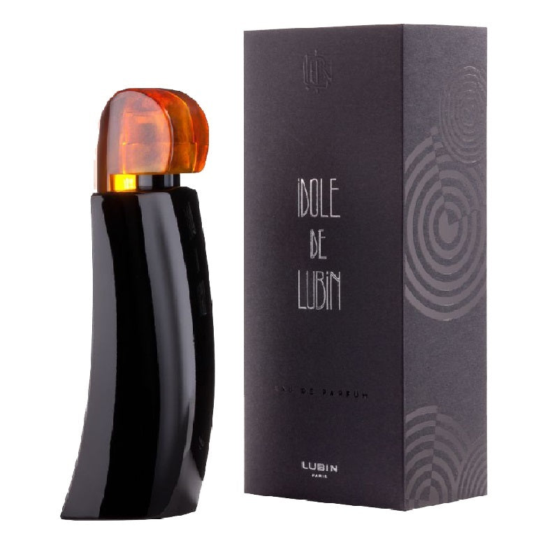 Black perfume bottle with orange cap next to its packaging on a white background