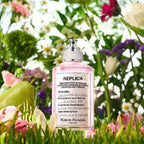 Pink spray bottle labeled 'REPLICA' surrounded by flowers and greenery
