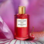 Red perfume bottle with gold cap labeled 'Cherry Cherry' by Mancera Paris, with a cherry and floral background.