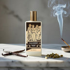 Perfume bottle with decorative label on a marble surface with vanilla bean and cardamom seeds.