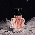 Miu Miu perfume bottle on a moon-like surface with a starry night sky.