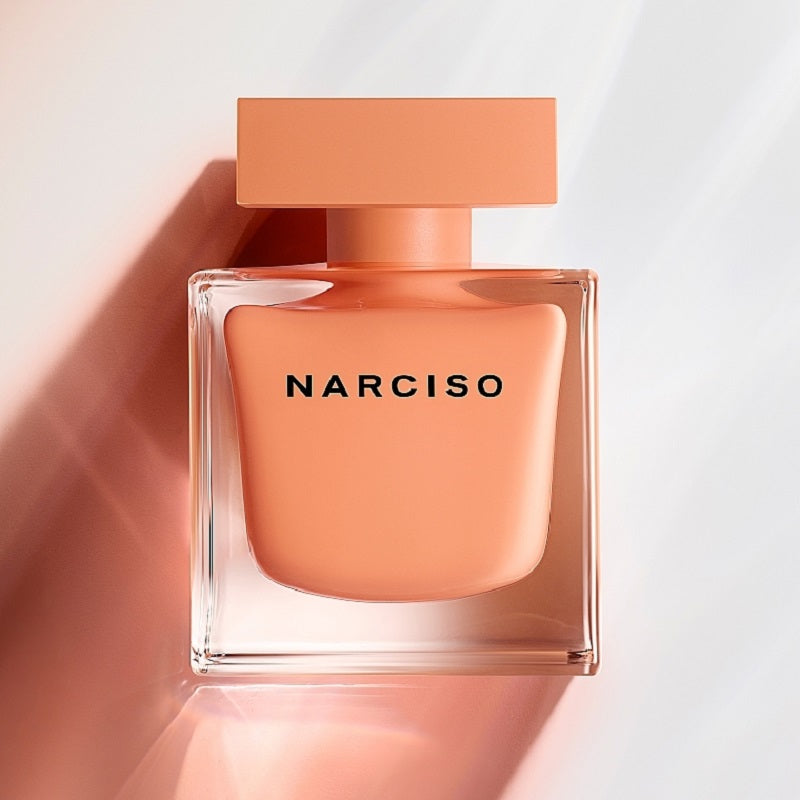 Narciso perfume bottle with a peach-colored cap and body on a light background