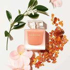 Narciso perfume bottle with flowers and amber stones on a light background