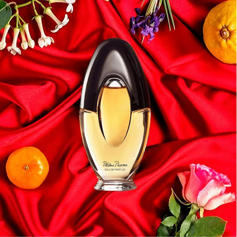 Perfume bottle on a red fabric background with flowers and fruits