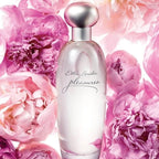 Estee Lauder pleasures perfume bottle surrounded by pink flowers.