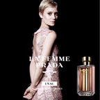 Advertisement for La Femme Prada L'Eau perfume with a model in a pink dress and the perfume bottle.