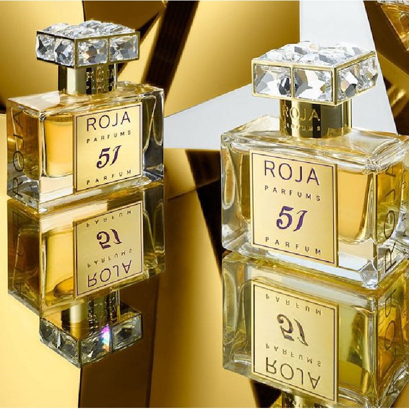 Two bottles of Roja Parfums 51 parfum on a reflective surface with a gold background.