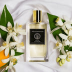 Perfume bottle labeled 'Mizensis' surrounded by flowers and leaves on a white fabric background