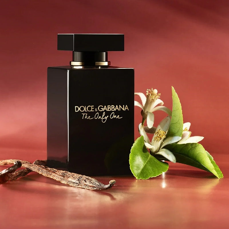 Dolce & Gabbana perfume bottle with flowers and leaves on a red background