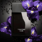 Tom Ford Noir perfume bottle surrounded by purple flowers on a dark background
