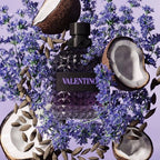 Valentino perfume bottle surrounded by purple flowers on a matching background