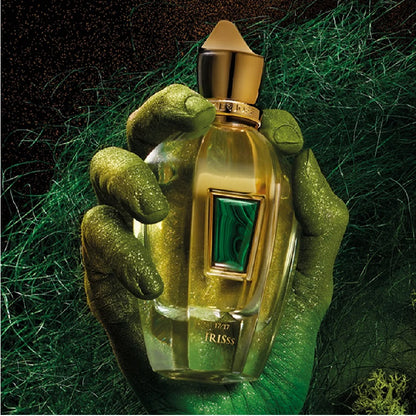 Gold perfume bottle with green accents held by a hand on a green textured background