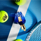 Blue perfume bottle with gold cap on a blue and white striped surface with tennis balls.