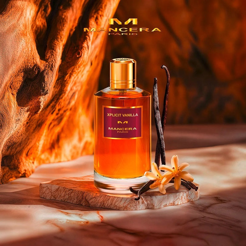 Mancera Xpliict Vanilla perfume bottle with vanilla beans and flowers on a wooden platform.