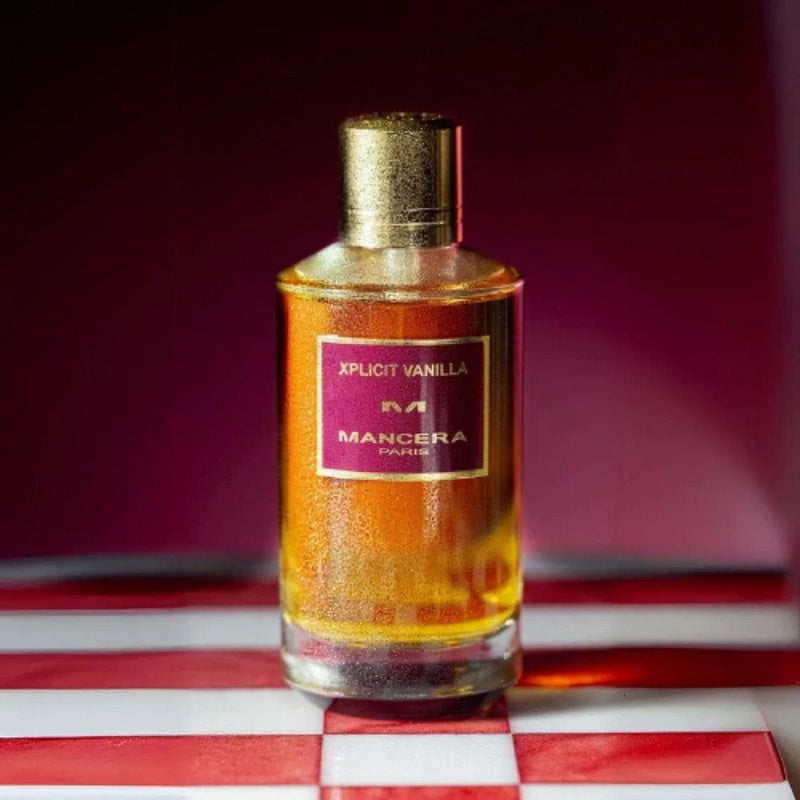 Perfume bottle labeled 'Xpli cit Vanilla' by Mancera on a red and white striped surface with a dark background.