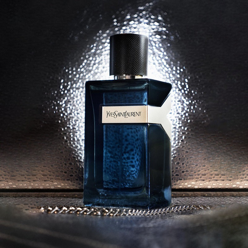 Blue Yves Saint Laurent perfume bottle on a reflective surface