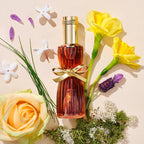 Perfume bottle with a gold bow surrounded by flowers on a beige background