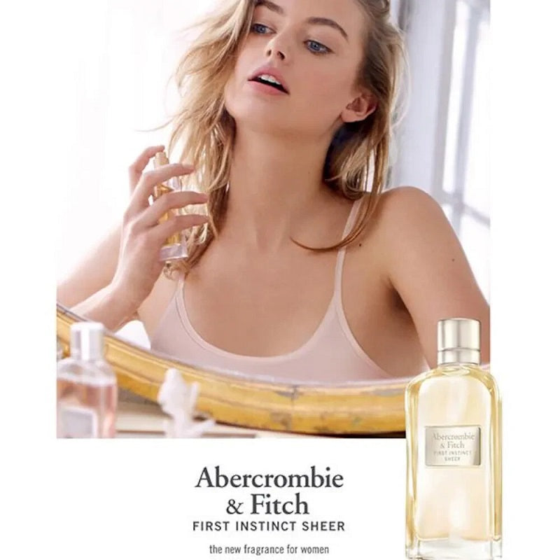 Woman applying First Instinct Sheer 100ml perfume with Abercrombie & Fitch product in the foreground