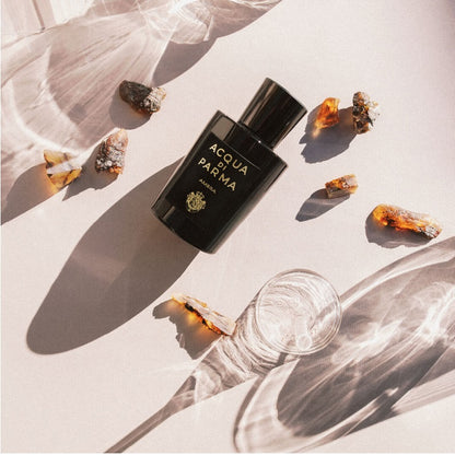 Lifestyle Image of bottle of Ambra together with images of fragrance contents on a table cloth background