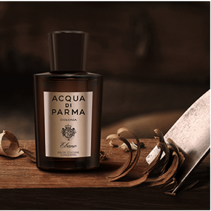 Lifestyle image of bottle Acqua di Parma cologne bottle on a wooden surface with dried leaves and a book.