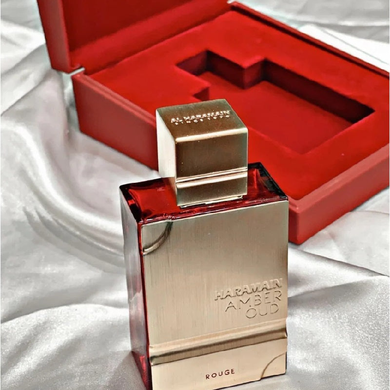 Haramain Amber Oud perfume bottle with red interior of the box on a white fabric background