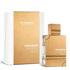 A product image featuring Al Haramain Amber Oud White Edition Eau de Parfum in a glass bottle with a gold-colored label and cap, alongside its white box packaging with the product name and brand.